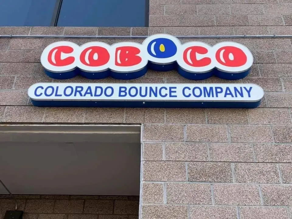 Red and blue channel letter sign for Colorado Bounce Company mounted on a brick building