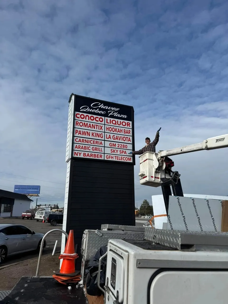 Technician repairing a tall pylon sign from a bucket truck