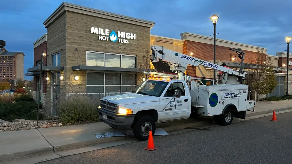 Smart Signs Denver bucket truck parked at a commercial job site at dusk