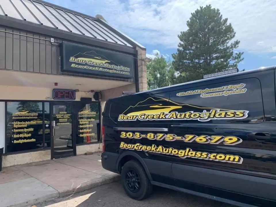 Bear Creek Auto Glass van with custom vehicle lettering parked outside its storefront